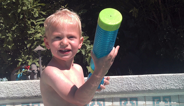 Boy having fun with a water gun at a Kidtastics swim party!