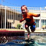 Boy happily jumping into a pool