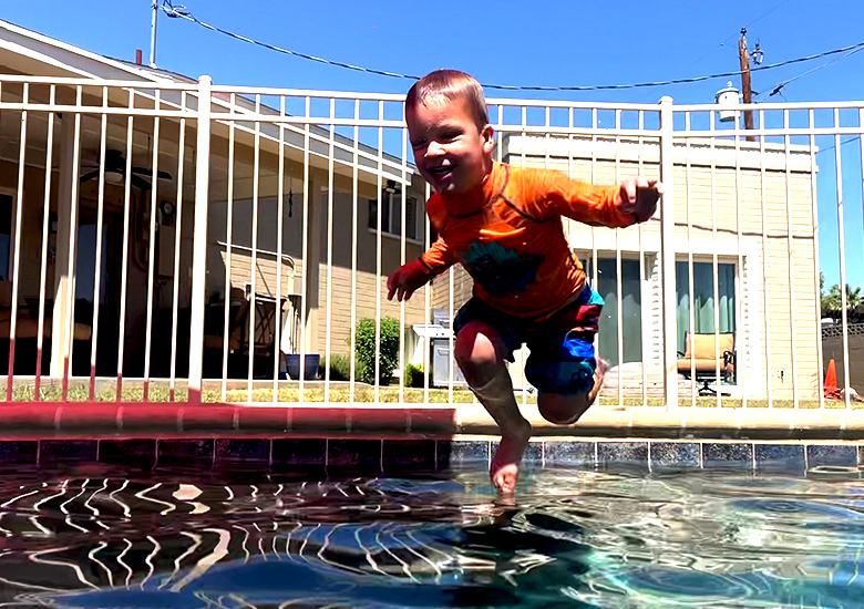 Boy happily jumping into a pool