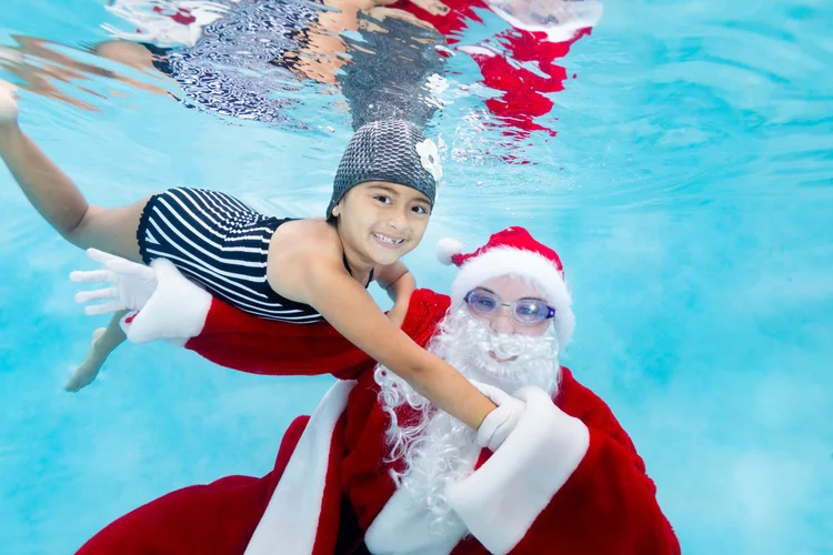 Children posing underwater with Santa in festive goggles during a Kidtastics holiday photo session.